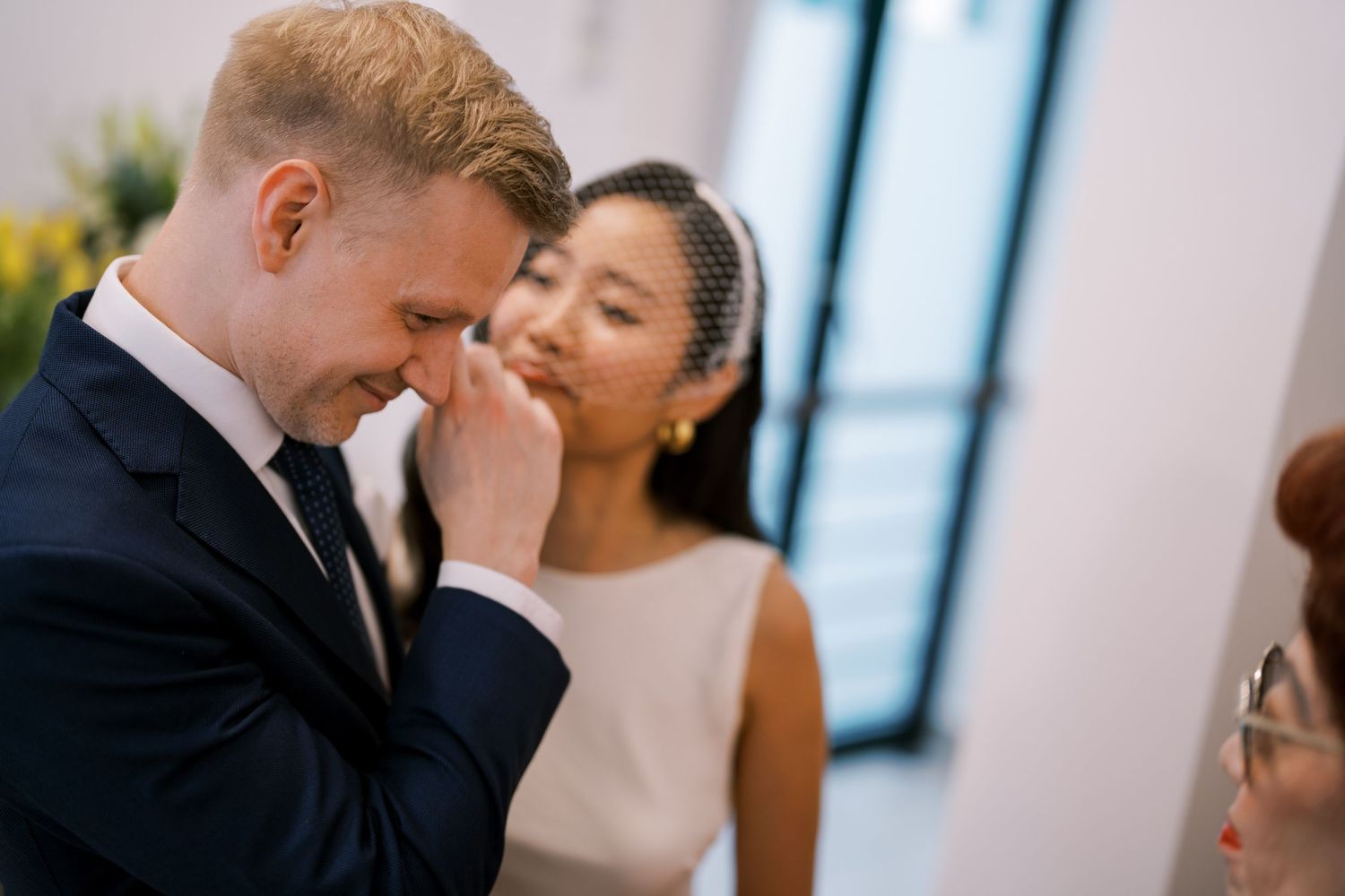 A tender moment between a couple during their wedding ceremony in a light-filled room.