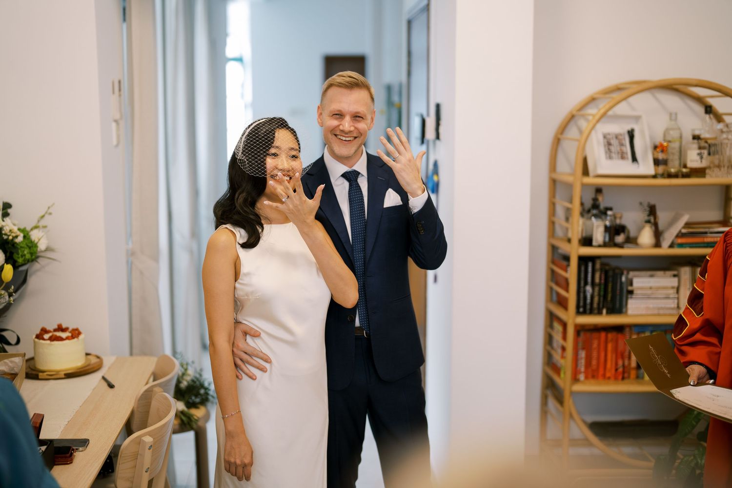 Joyful wedding couple laughing together in a bright hallway with modern decor.