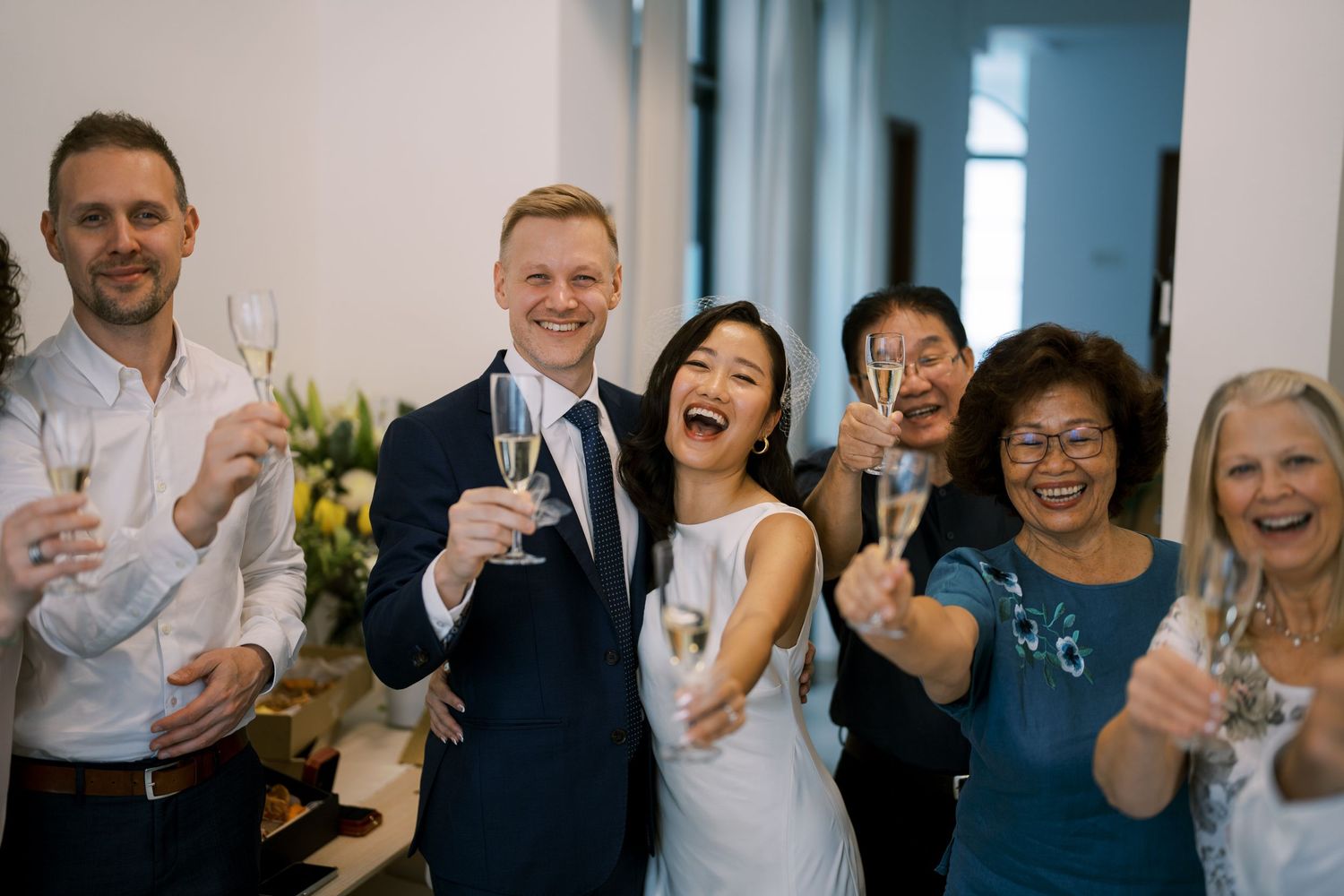 Wedding celebration with guests toasting and sharing joyful moments in a bright space.
