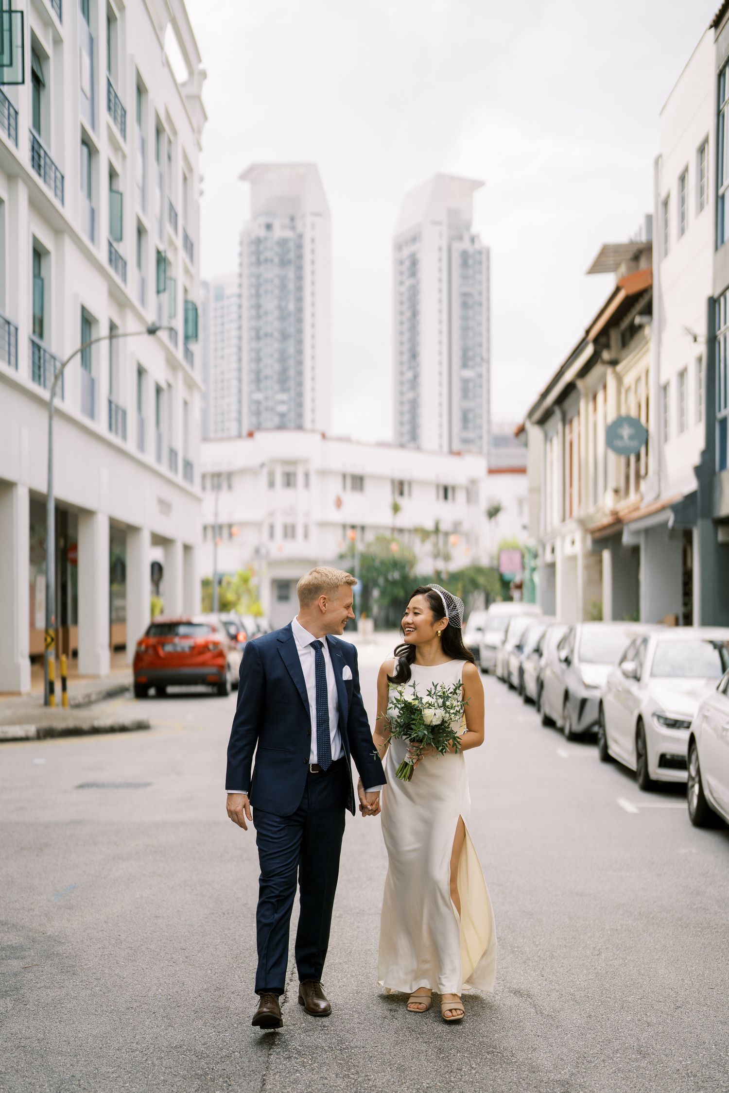 Urban wedding photography with modern architecture and city skyline in the background.