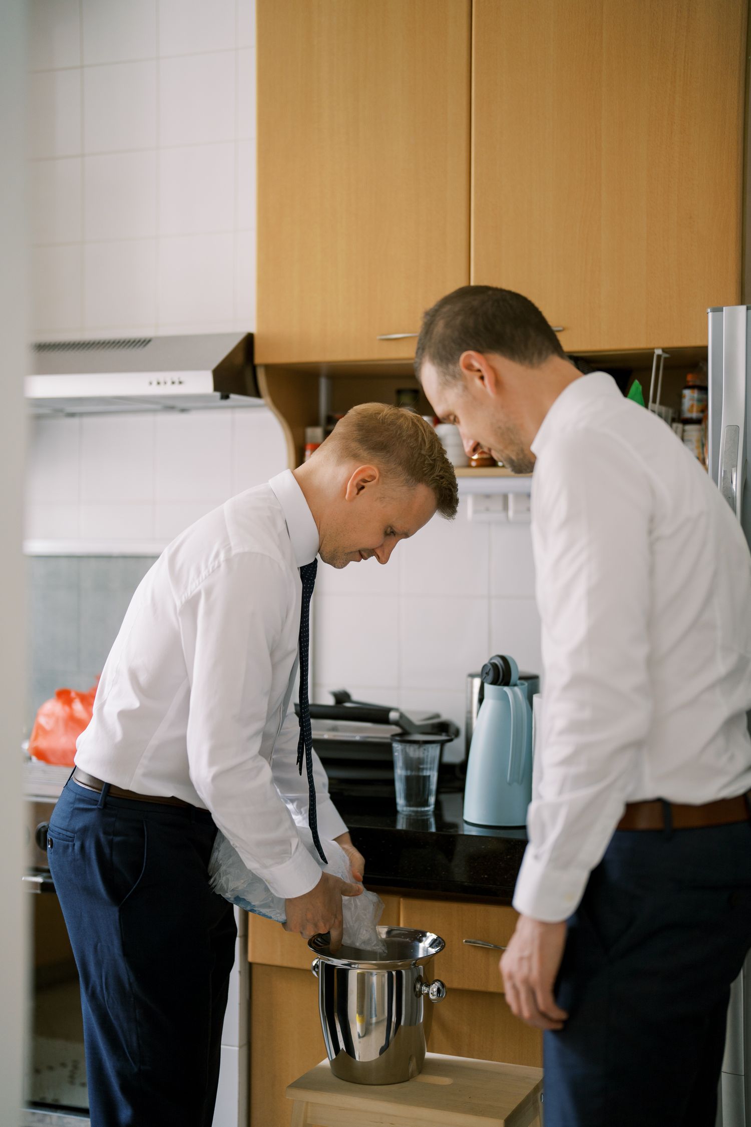 Two people in white shirts preparing beverages at a modern kitchen counter.