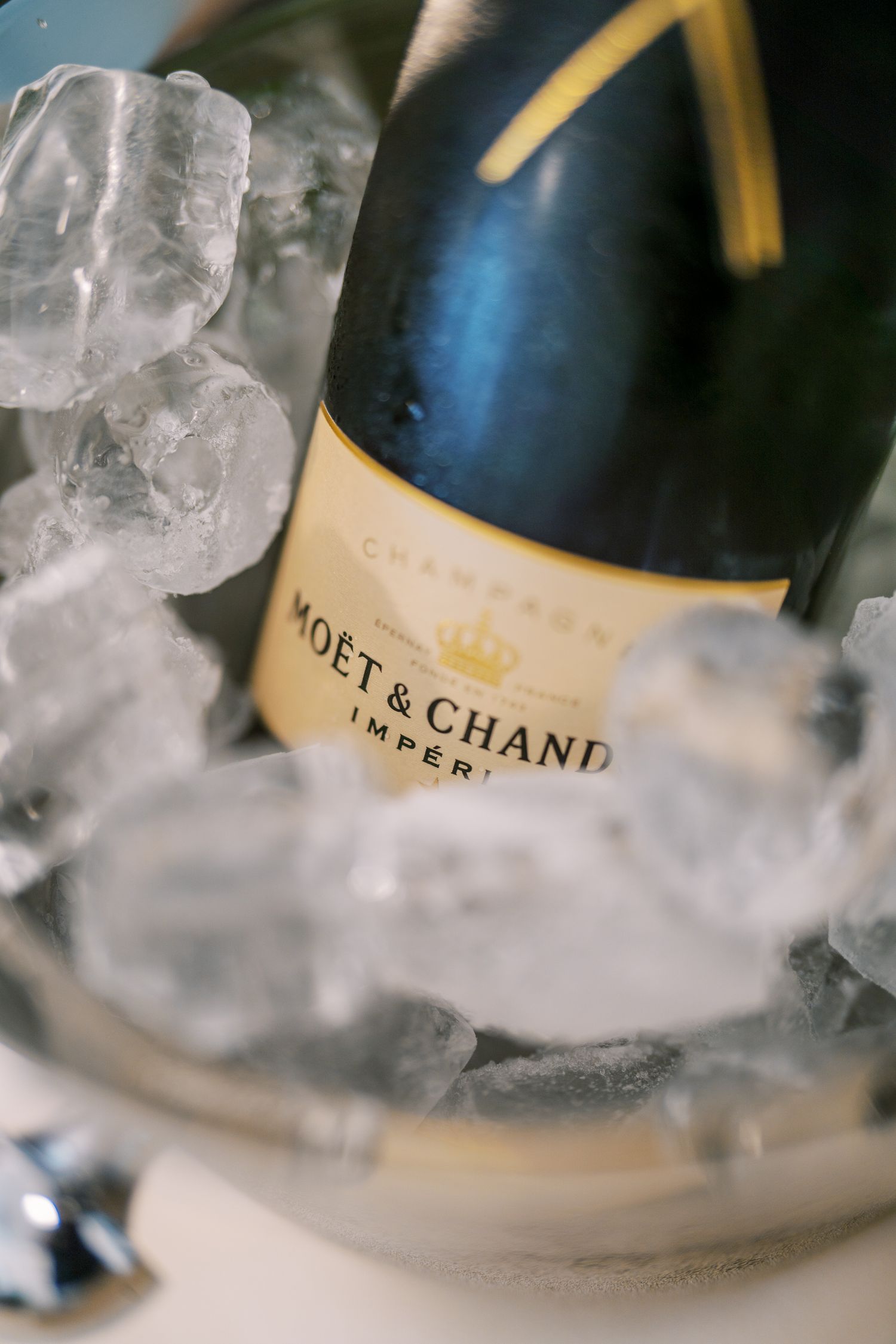 Close-up of champagne bottle nestled in ice with Moet & Chandon label visible.