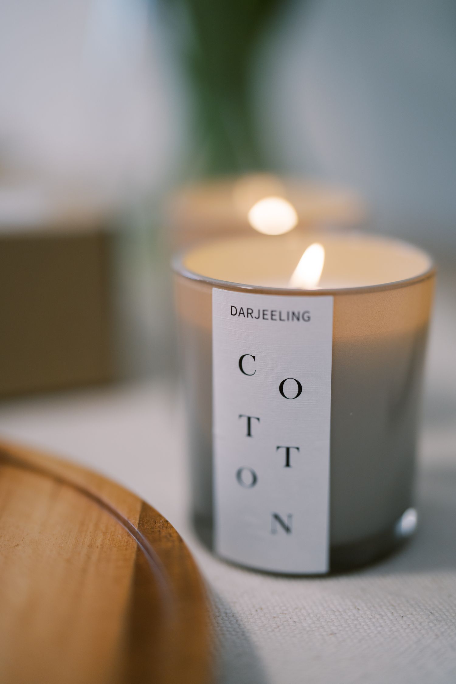 Lit candles with 'Darjeeling' and 'Cotton' labels in soft focus.