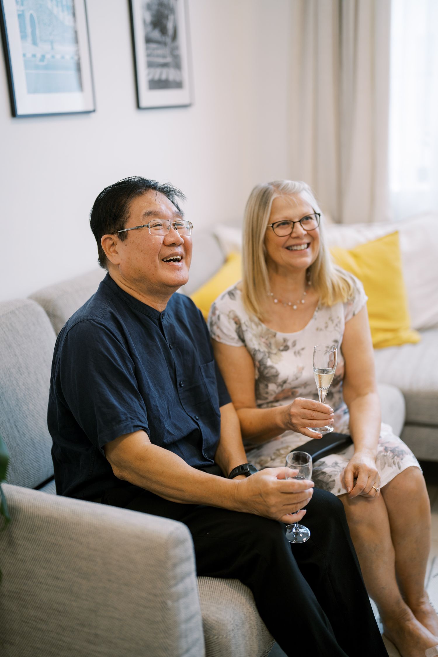 Casual social gathering with people sharing laughs on a grey couch.