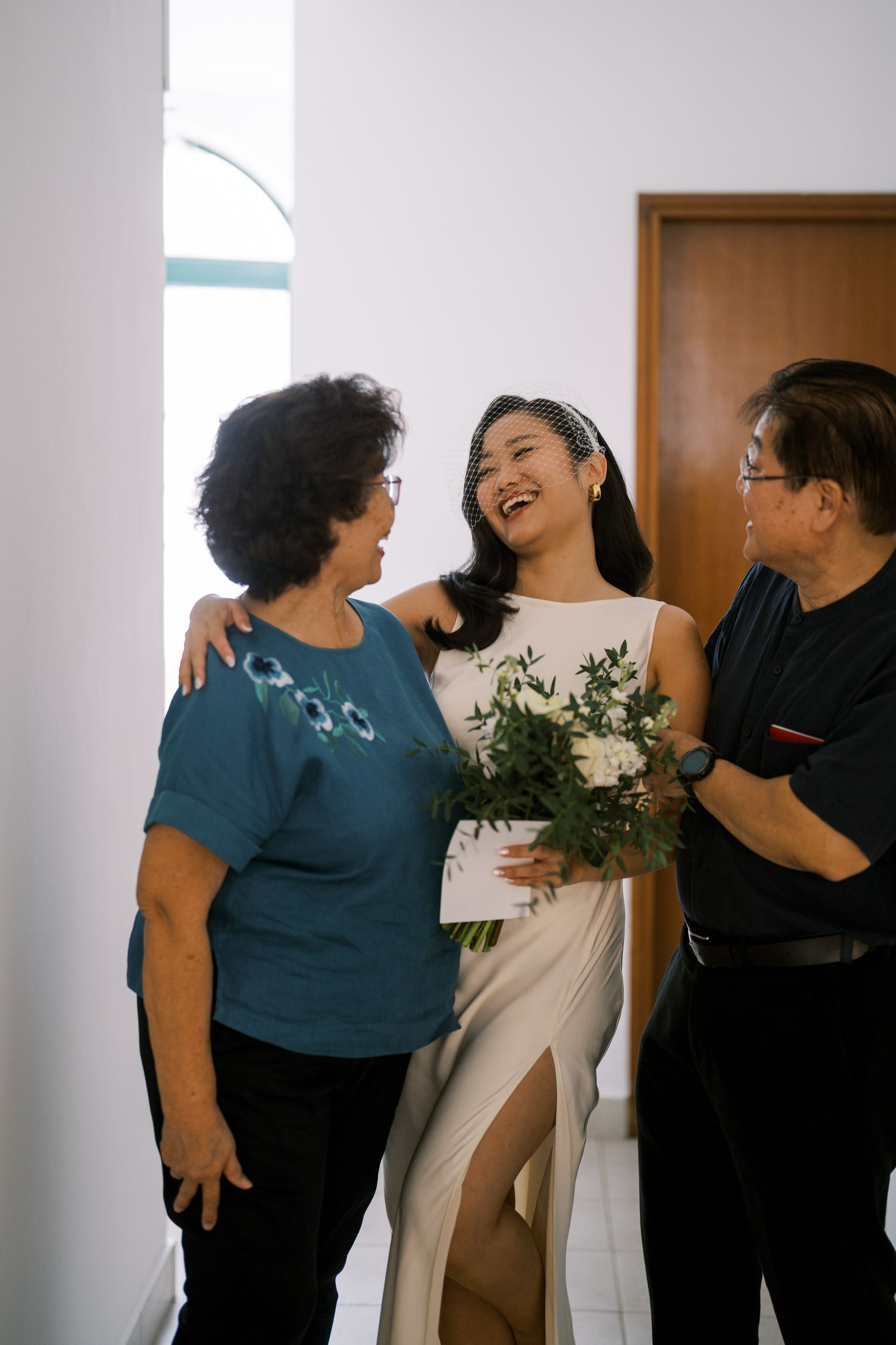 A joyful moment shared between wedding guests and the bride holding a white floral bouquet.