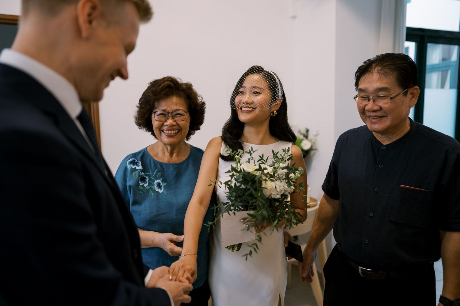 Wedding guests share laughter and conversation in a bright hallway.