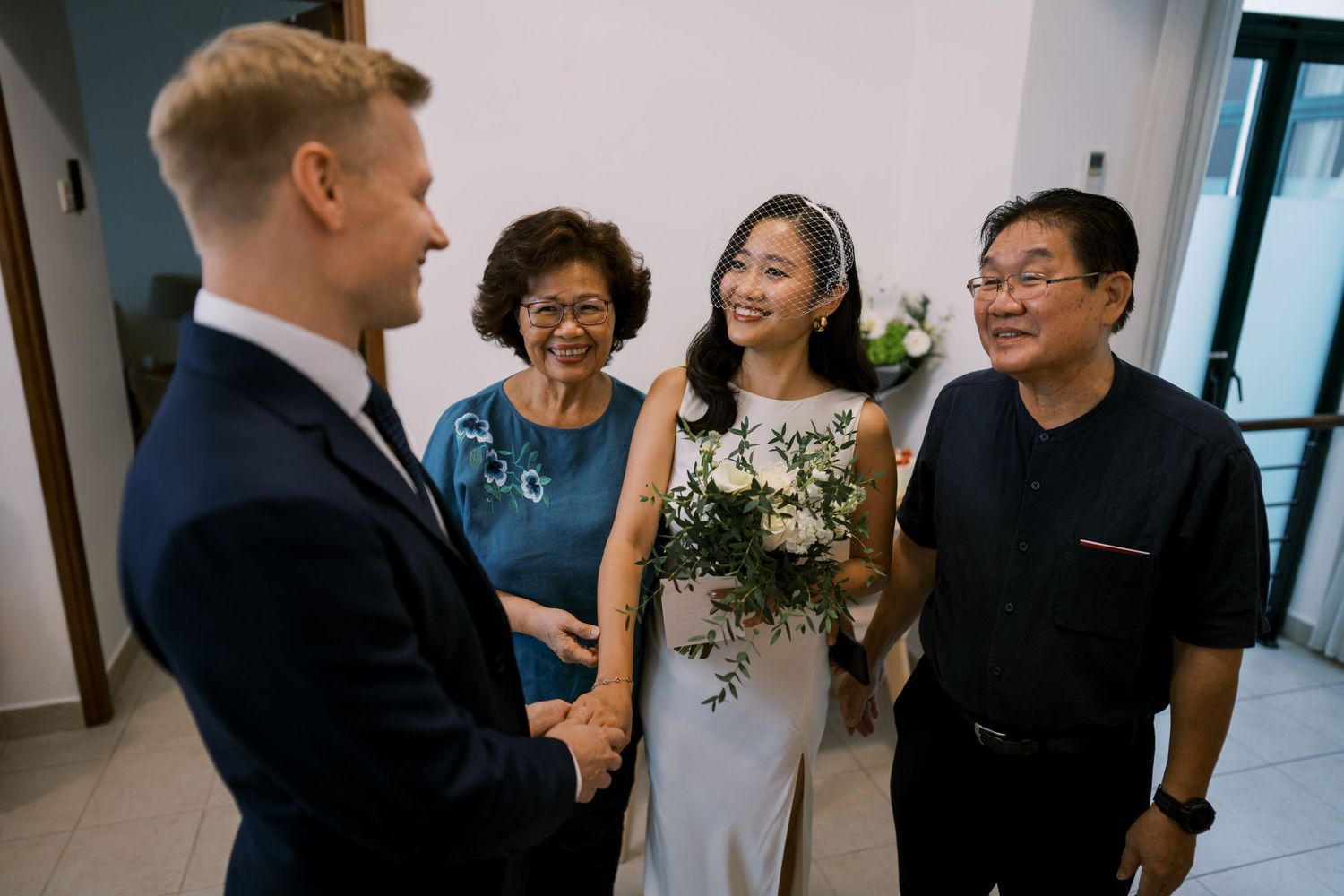 A small group gathers in a hallway during a wedding celebration.