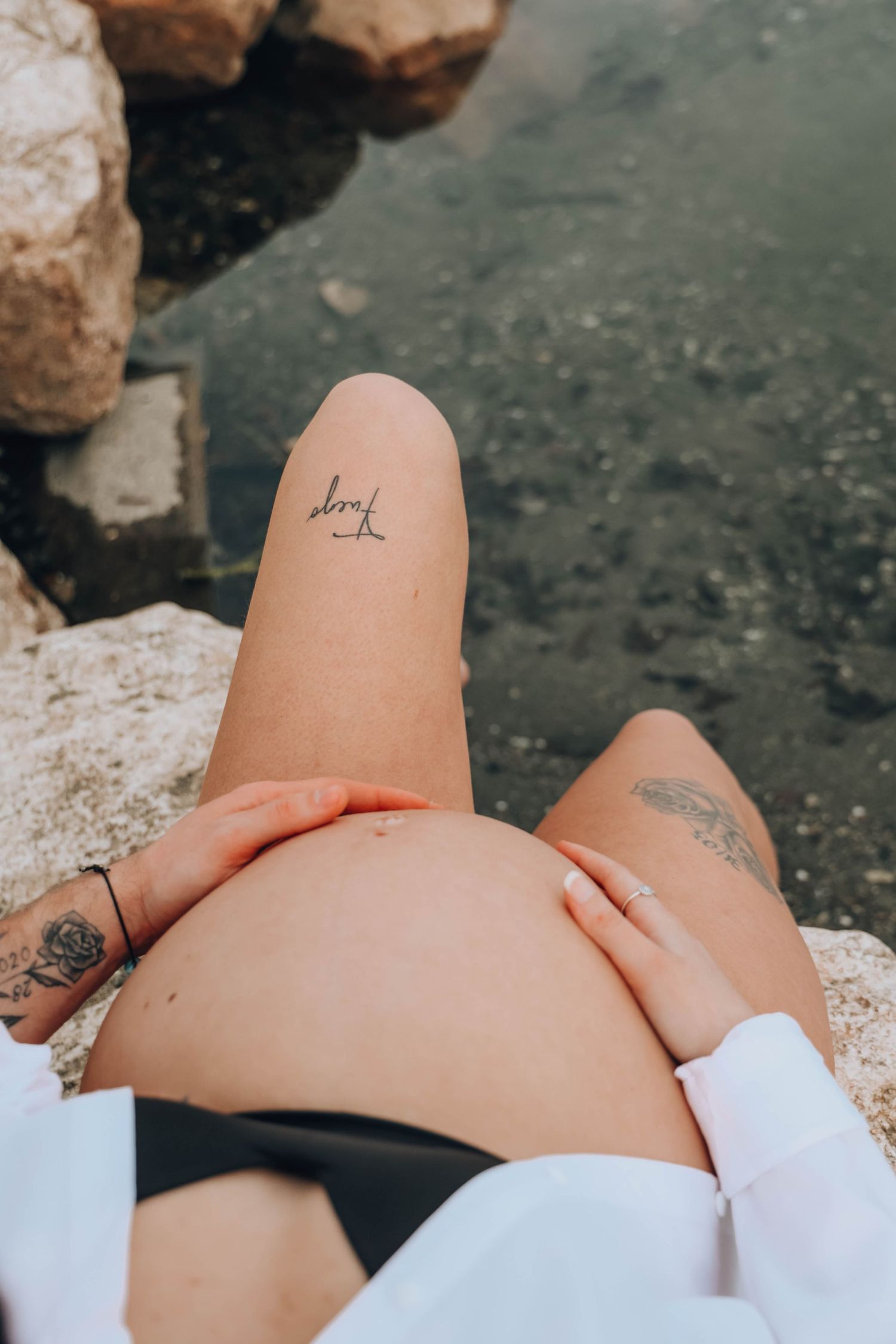 Small minimalist tattoo on bare skin against textured stone background.