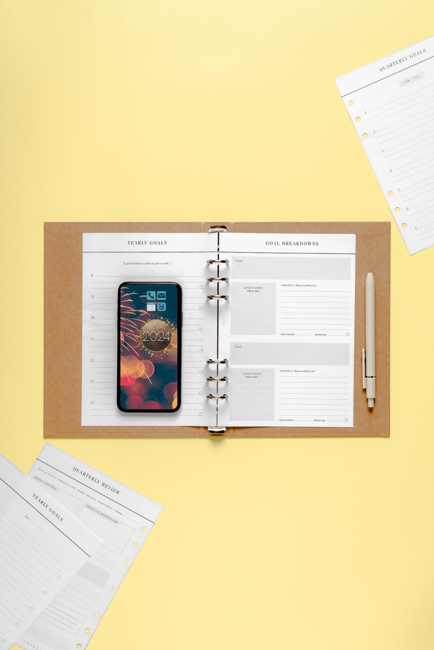 iphone on top of open journal with goal oriented inserts on a yellow backdrop, minimal, motivating, organised
