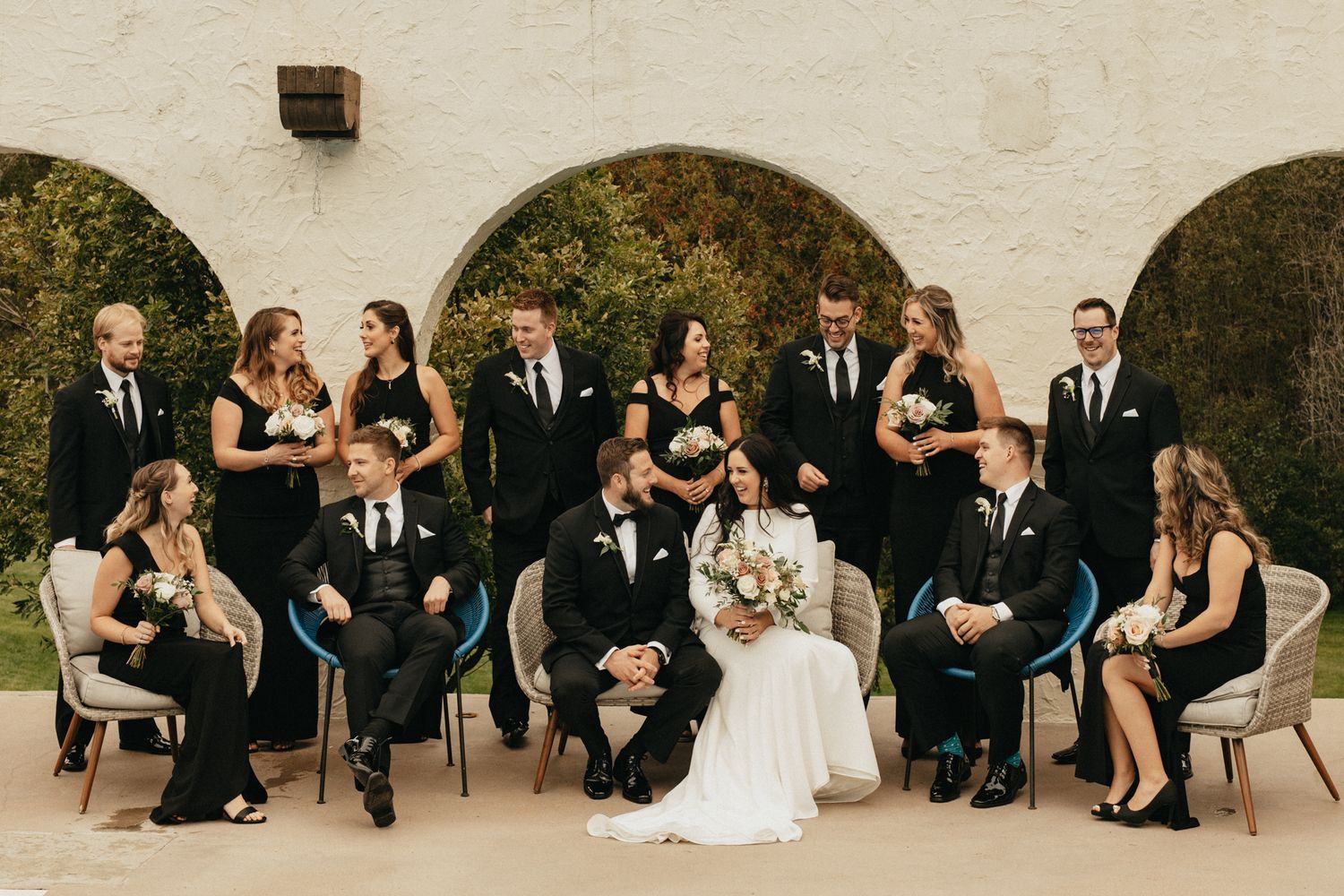 Wedding party group photos with bridesmaids and groomsmen against a light colored wall.