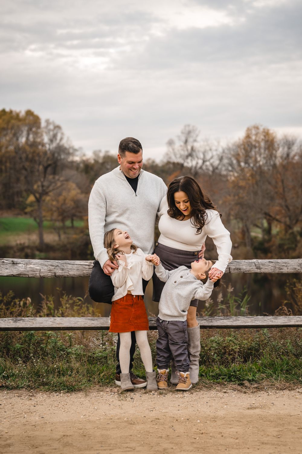 Playful family moments captured on rustic wooden fence during autumn photoshoot.