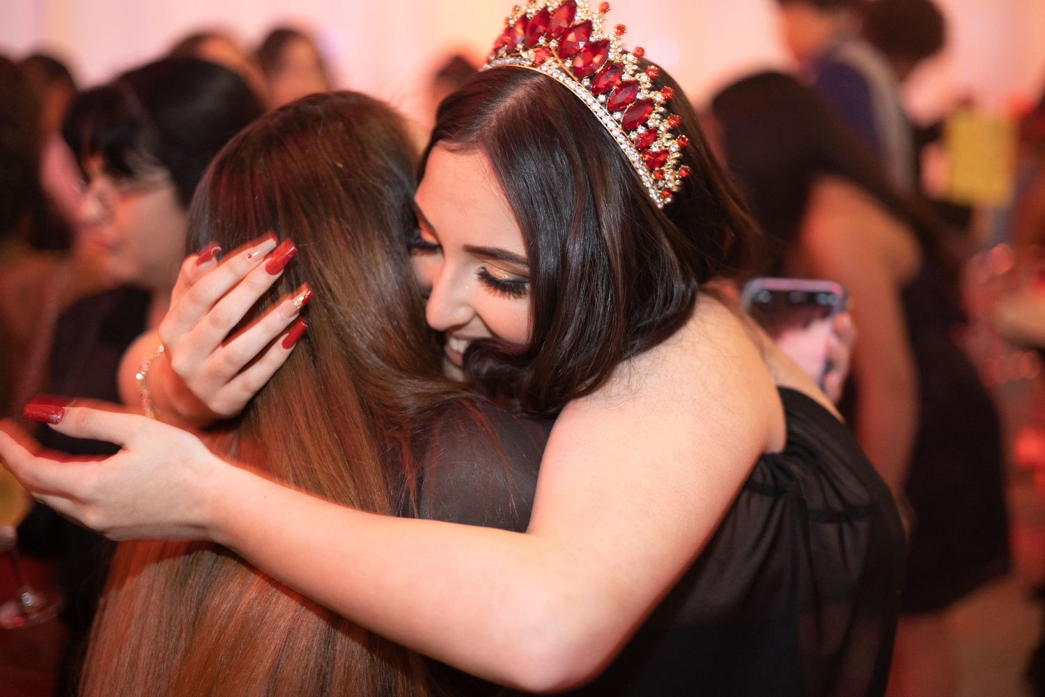 An emotional embrace during a celebration with pink lighting.