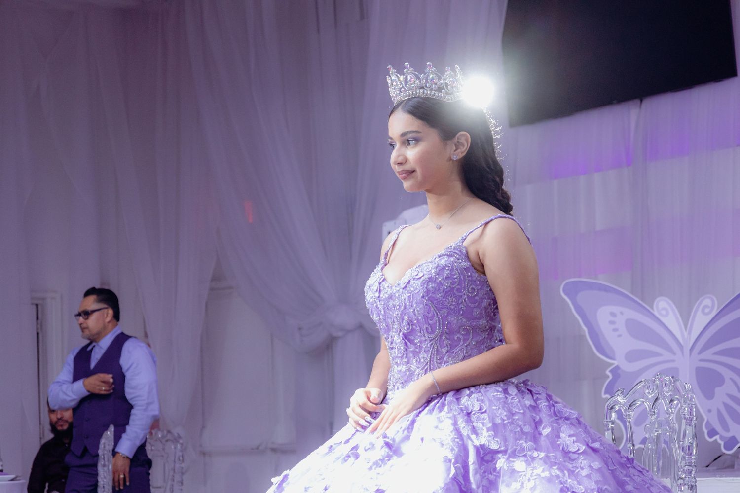 A formal celebration featuring an elegant purple ball gown and decorative butterfly themed backdrop.
