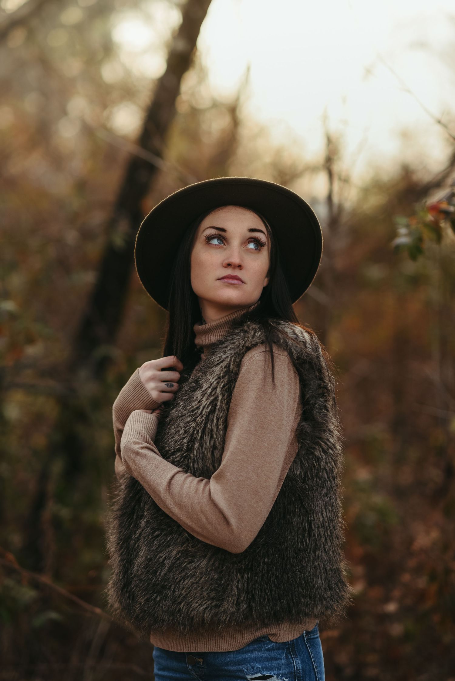 Artistic portrait of someone in autumn wearing a wide-brim hat and fur vest.
