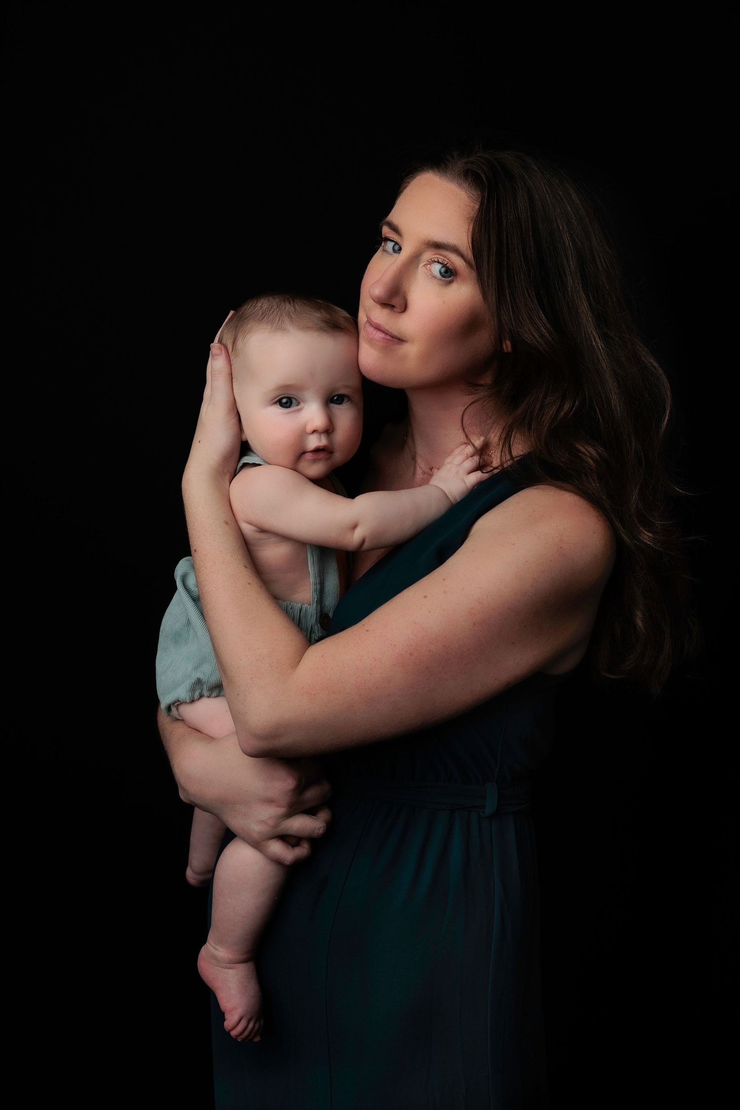 Women grins while holding her baby during a studio photography session