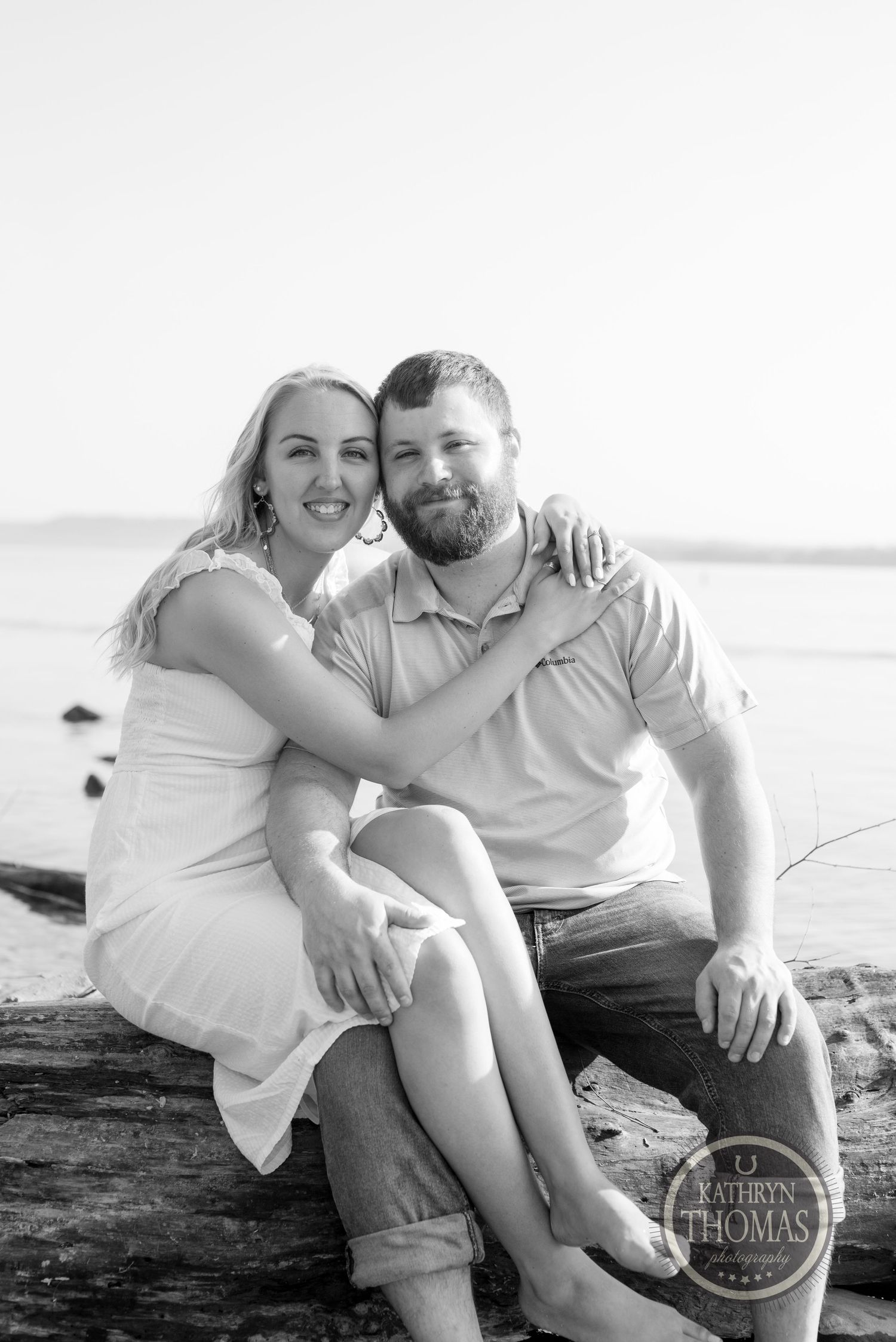 A black and white portrait showcasing a tender embrace by the water.