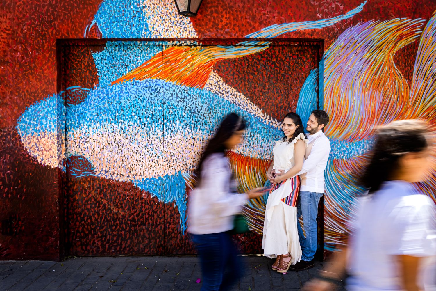Dynamic wedding dance photos against vibrant blue and red wall mural.