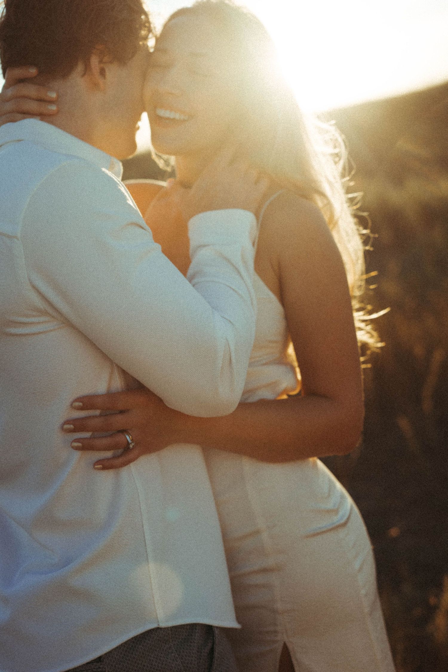 Intimate couple embrace during golden hour sunset in romantic outdoor setting.