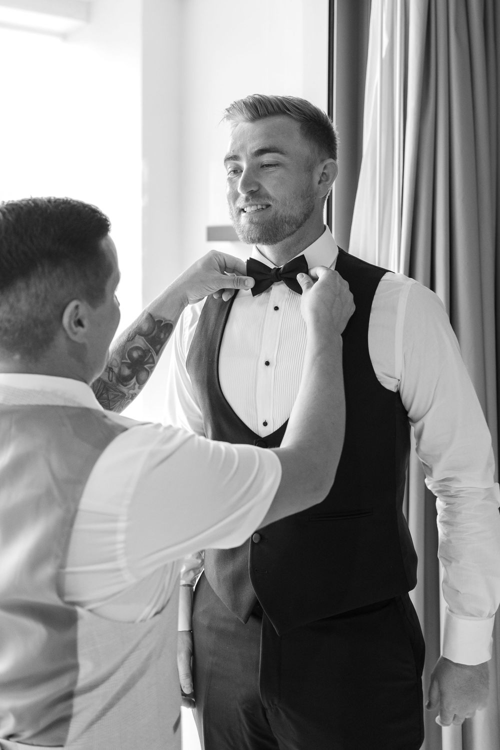 Groom with best man adjusting bow tie