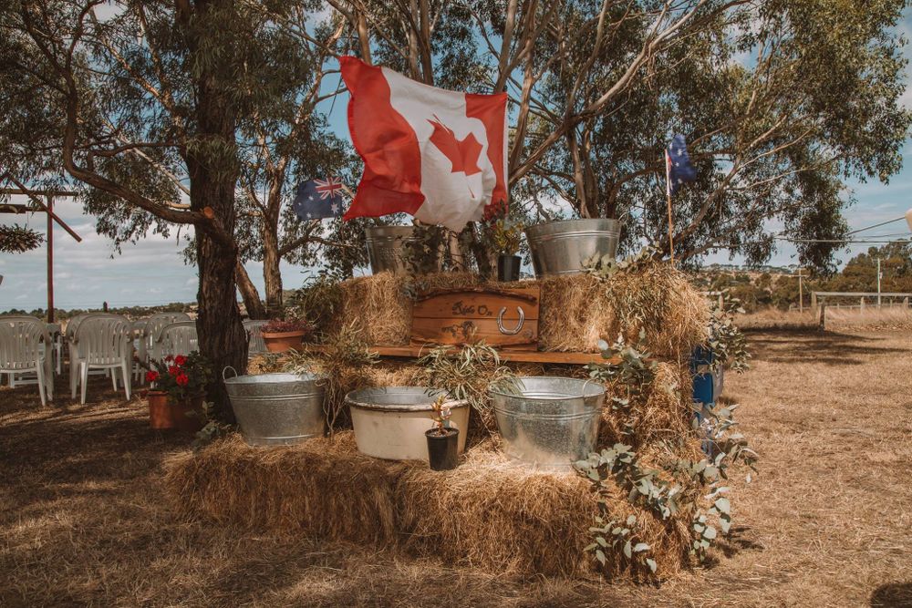 Rustic wedding decoration featuring hay bales and a Canadian flag in an outdoor setting.