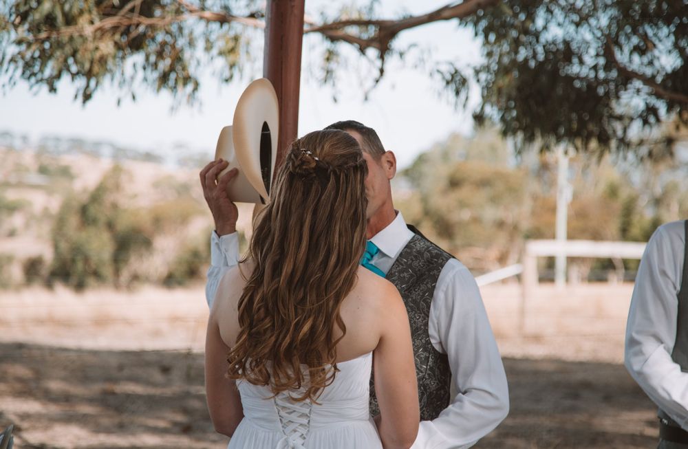 Wedding ceremony under a rustic wooden arch in an outdoor setting.