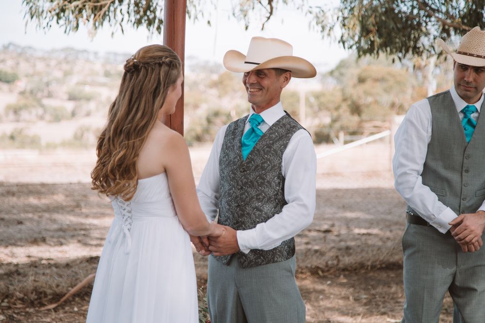 Rustic country wedding ceremony in a desert landscape with western themed attire.