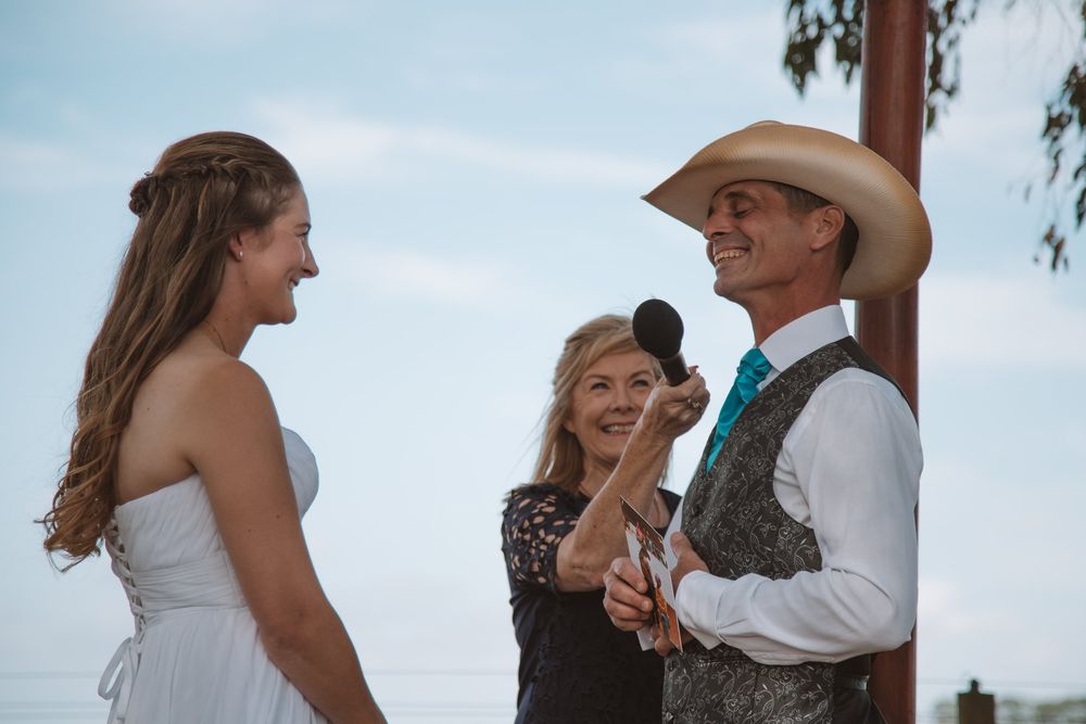 Joyful moment during outdoor country wedding ceremony under wooden arch.
