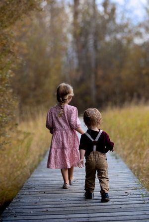 Two children with backs to camera walking down a boardwalk