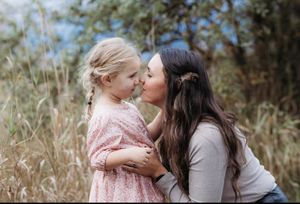 Mom and daughter gaze at each other amid autumnal grass