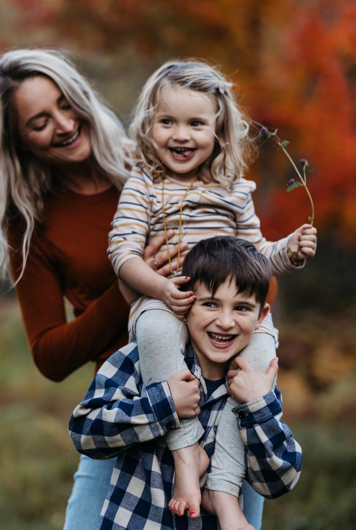 Happy children giving piggy back ride while mum smiles