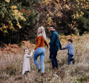 Family of four walking away from camera in an autumnal field