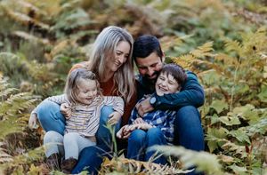 Mom, dad and their two children sitting in the ferns