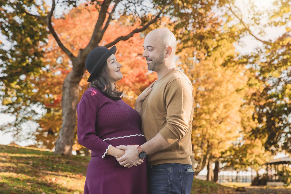 Couple in autumn clothing poses together among fall foliage.