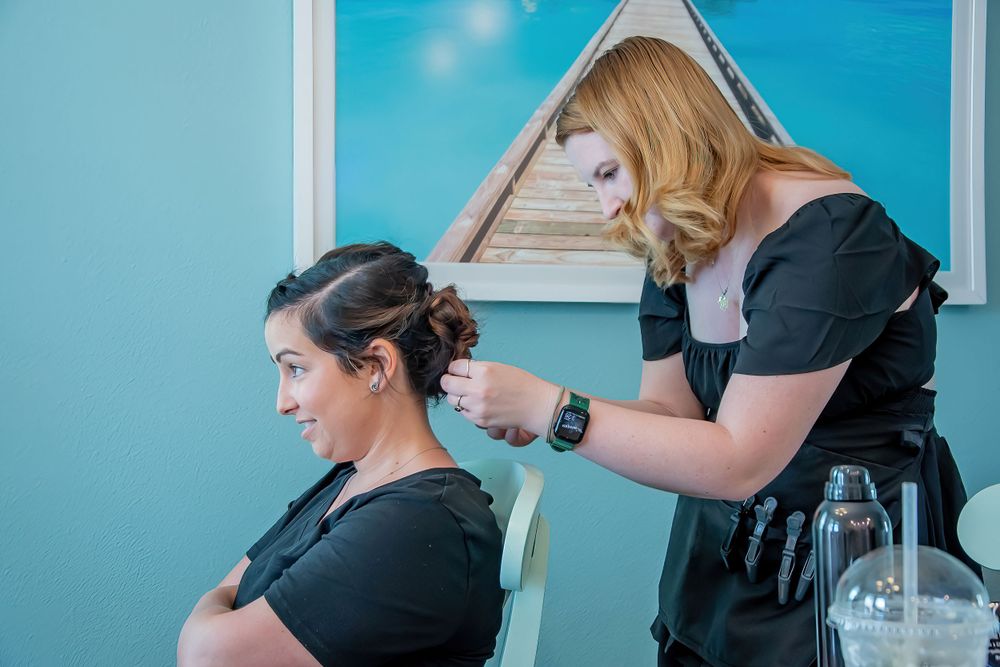Vazul Hair Artistry styling client's hair in front of turquoise wall at Margaritaville Orlando Resort.