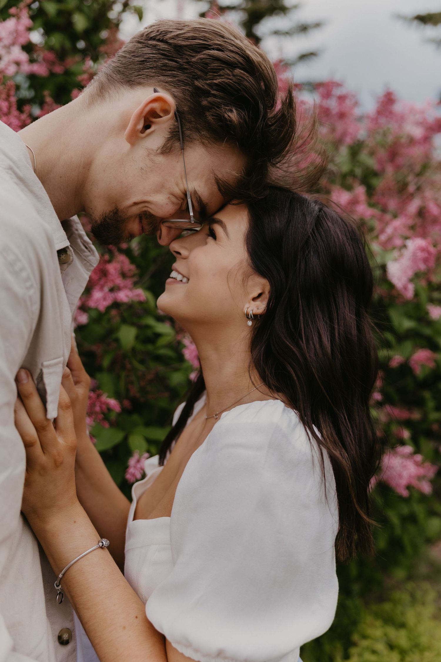 Romantic couple sharing an intimate moment among pink flowering bushes.