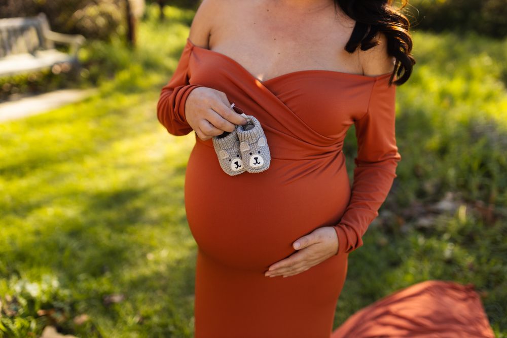 Close-up of a maternity dress and baby onesie during an outdoor pregnancy photoshoot.