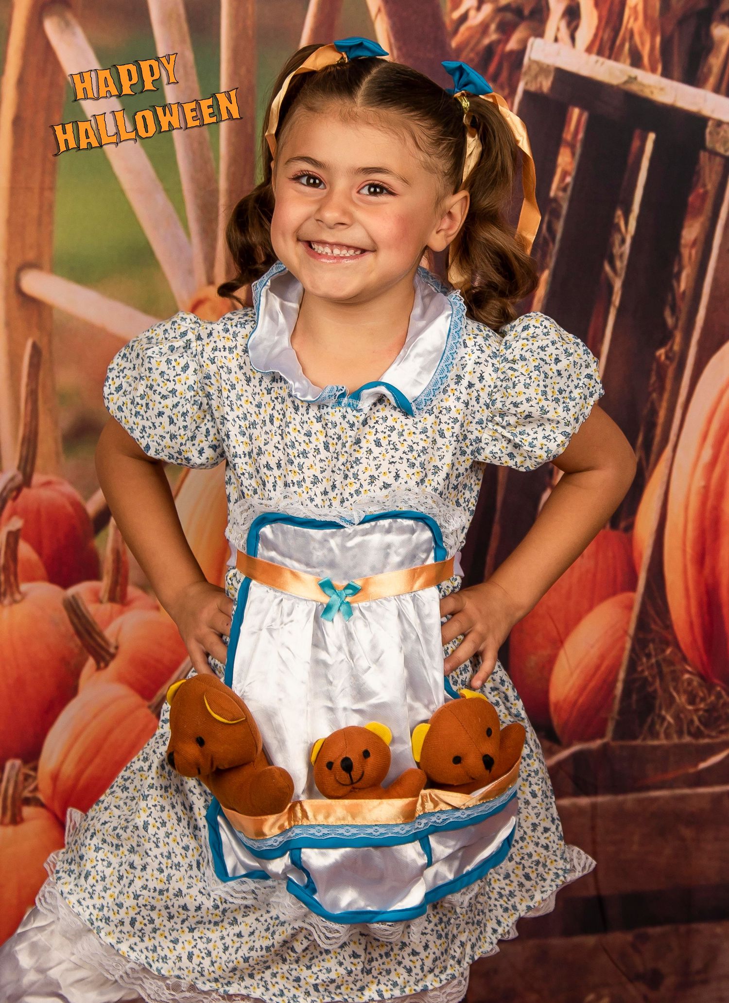 A child in a blue and white Alice in Wonderland costume holds a basket of plush pumpkins.