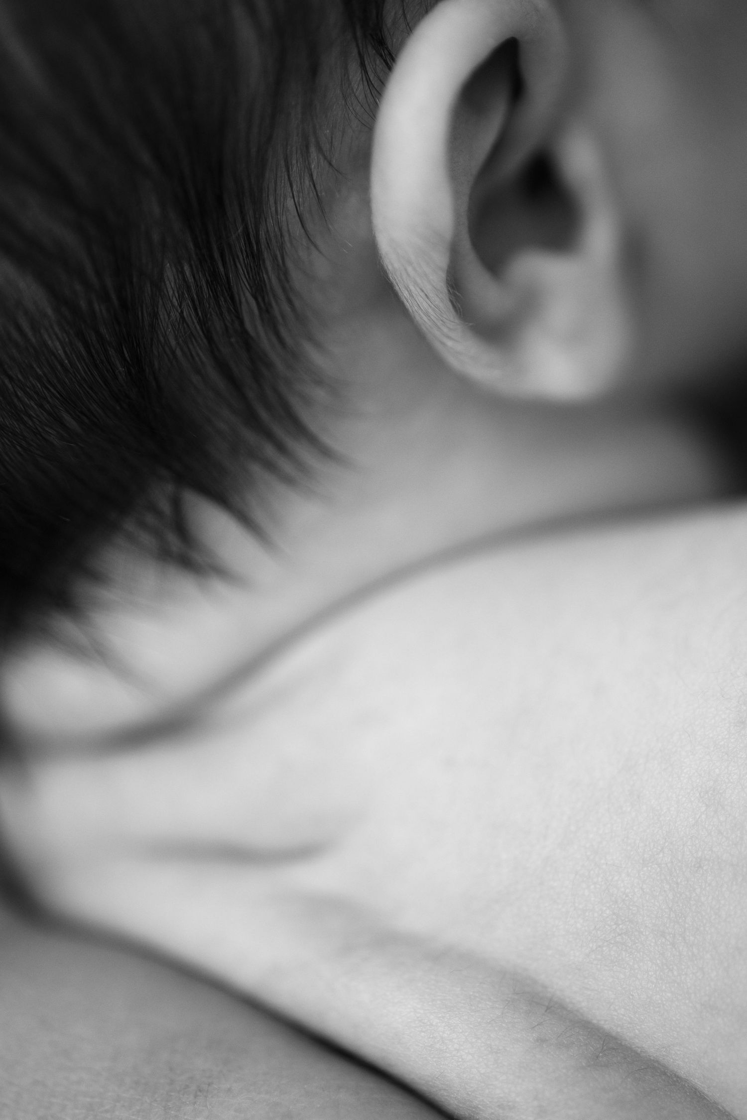 Close-up black and white macro shot of a baby's ear and soft skin.
