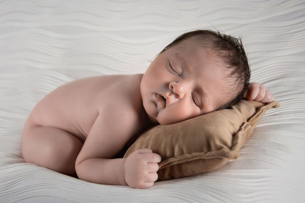 Professional studio photo of newborn baby with little cushion