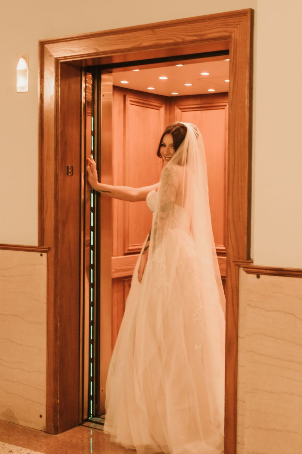 Wedding dress silhouette against wooden doorframe in warm interior lighting.