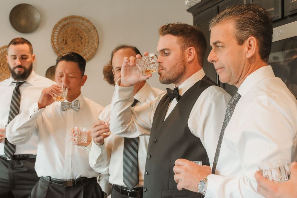 Groomsmen in suits getting ready together in a warm-toned indoor setting.