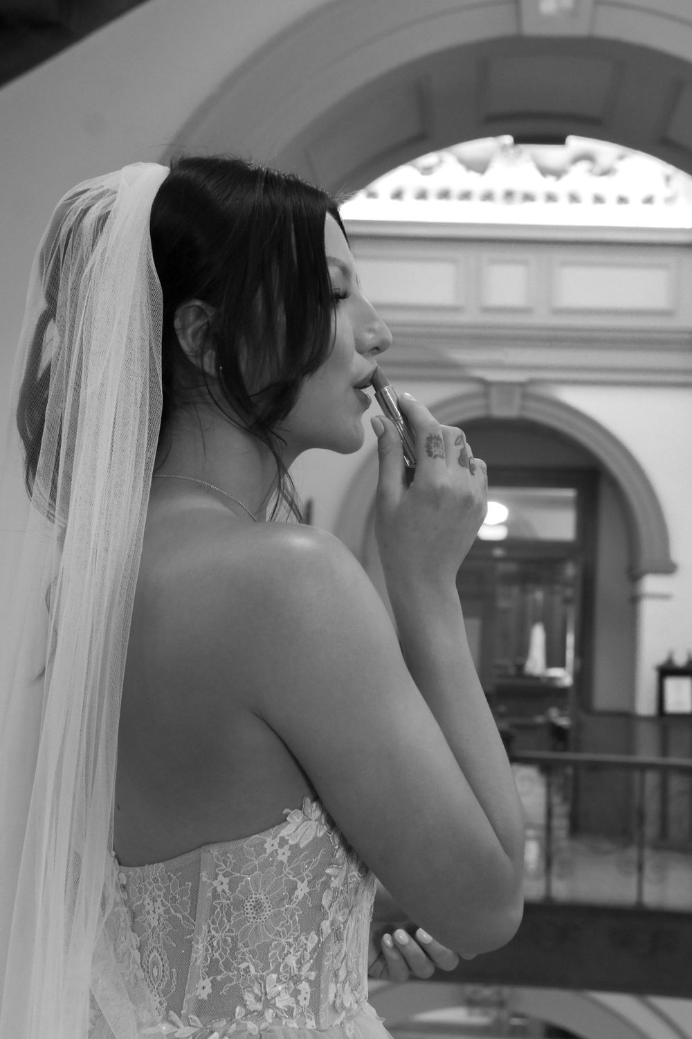 Black and white portrait of a bride against an architectural backdrop.