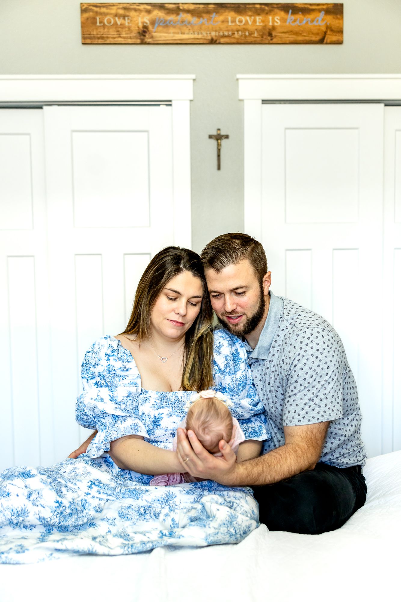 Parents hold their new baby girl and smile down at her during newborn photos in Colorado Springs.