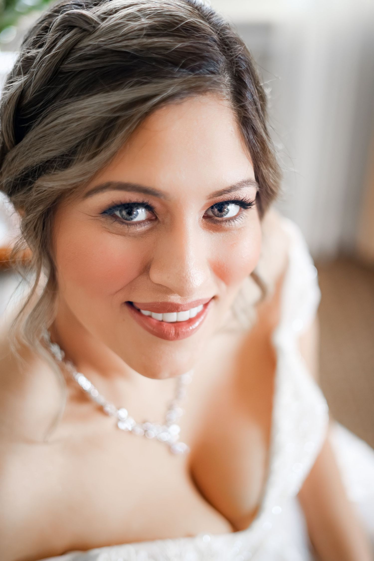 Close up of bride with elegant makeup, pearl necklace and white dress.
