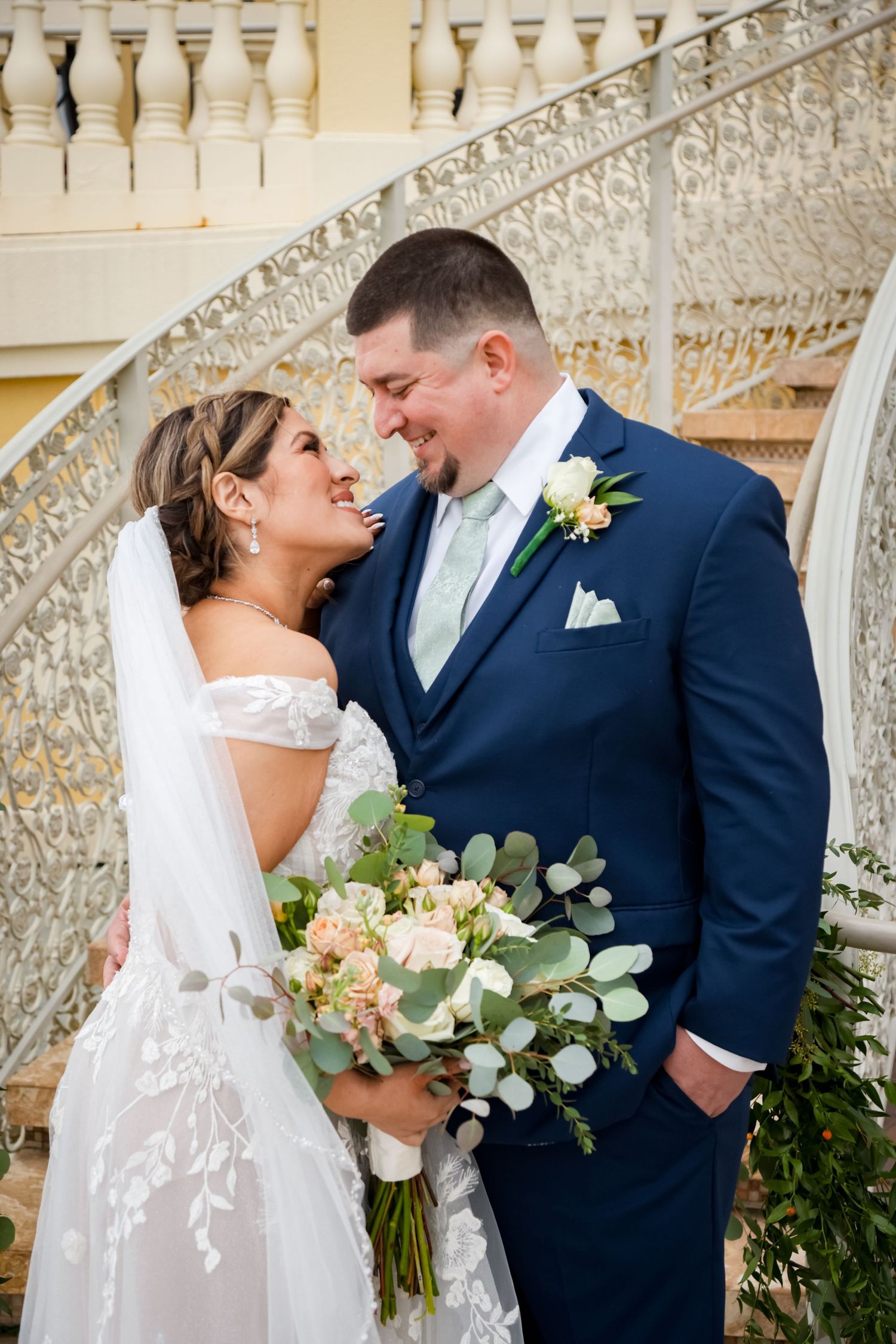 Wedding couple sharing romantic moment on ornate staircase.