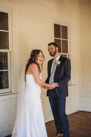 Emotional first look moment between bride and groom on a covered porch.