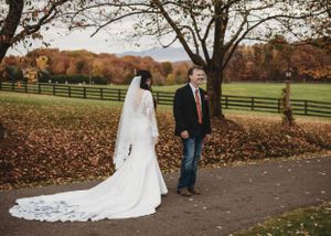 Wedding couple walking along a path surrounded by fall foliage.
