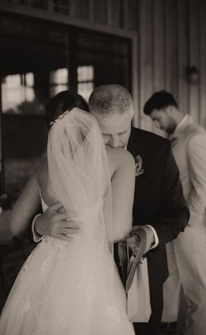 A tender black and white photograph capturing an intimate wedding moment on a covered porch.