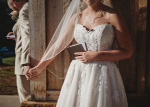Close-up detail of a lace wedding dress and veil against a rustic backdrop.