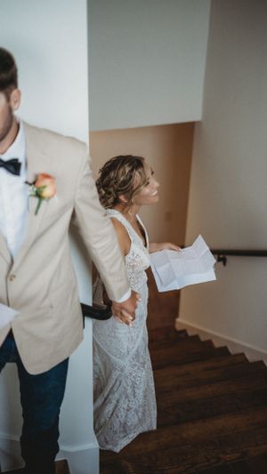 Wedding couple exchanging letters on wooden stairs indoors.